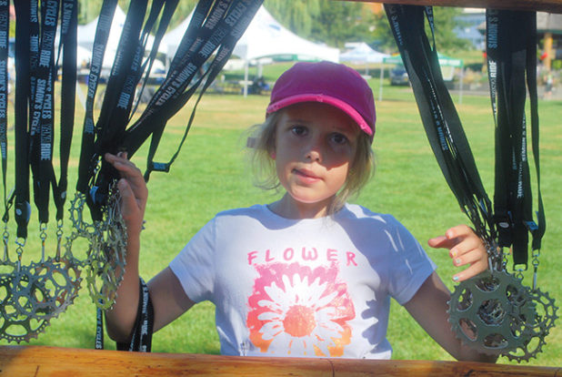 YANA recipient, Anna, giving out medals at the finish line of the Simon’s Cycles YANA Ride last summer.